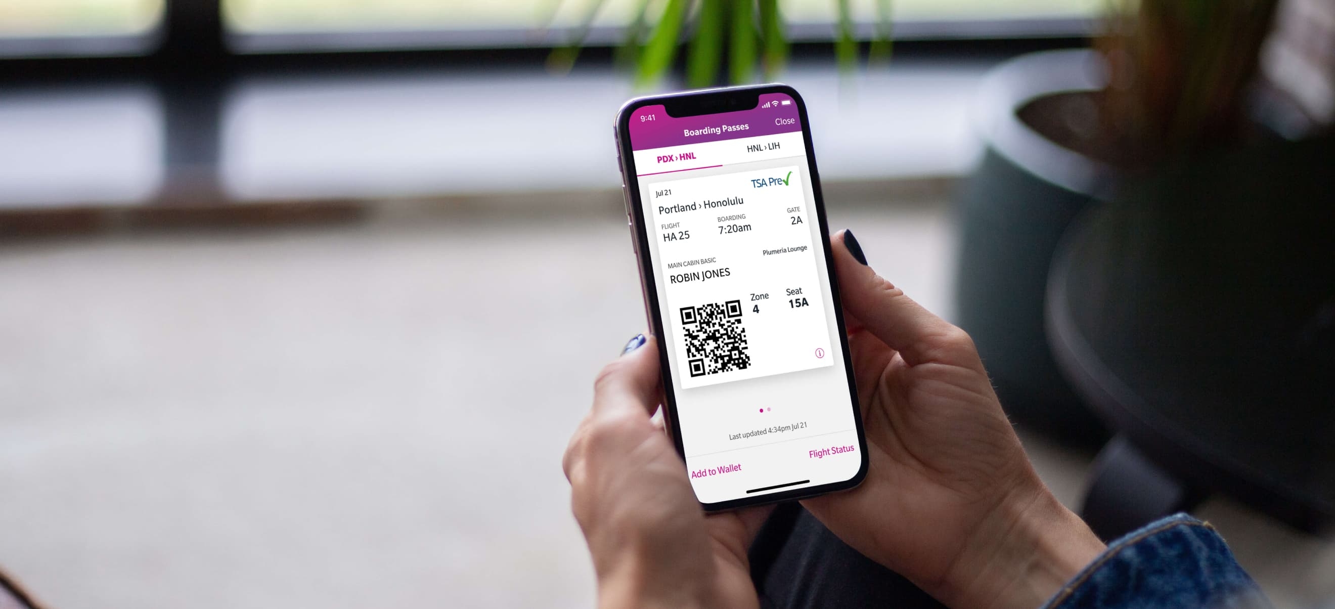 A person holds a smartphone displaying a digital boarding pass with a QR code on the Hawaiian Airlines app.