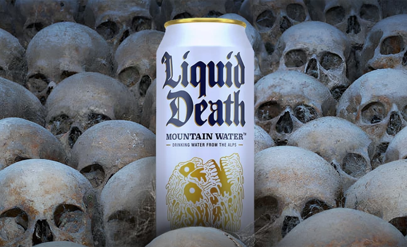 A can of Liquid Death is placed among an array of human skulls.