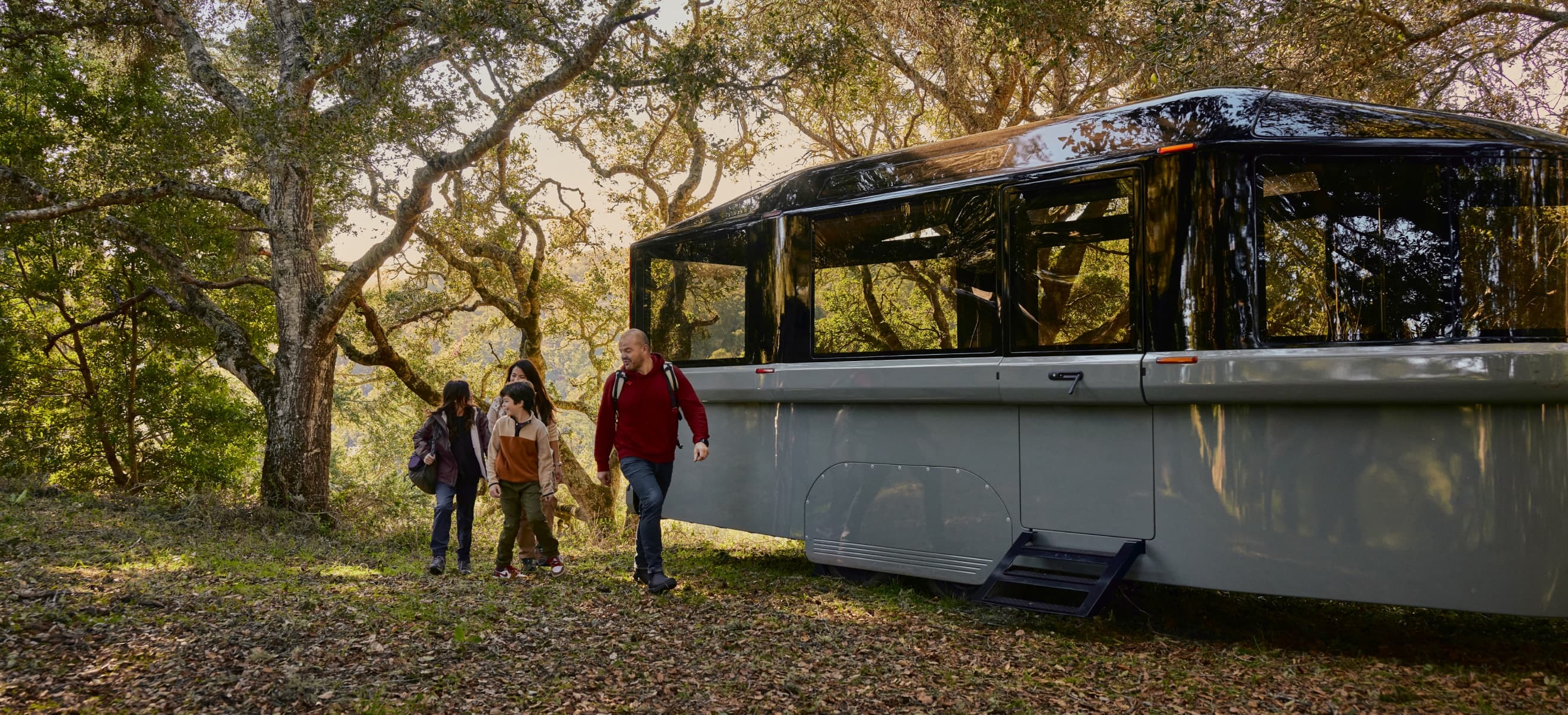 A family exits a modern Lightship RV parked in a wooded area.
