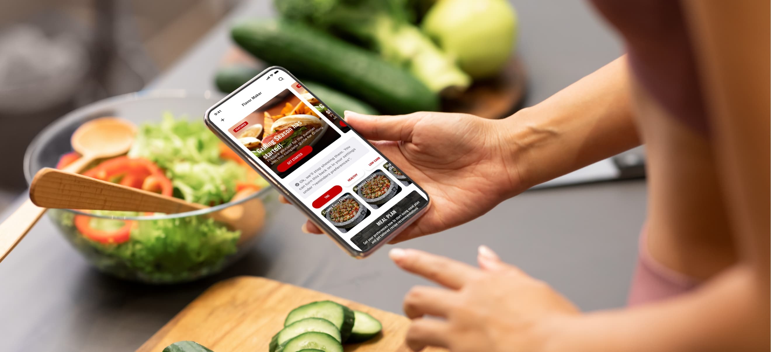 A person holds a smartphone displaying the McCormick app while preparing a fresh salad in a kitchen setting.