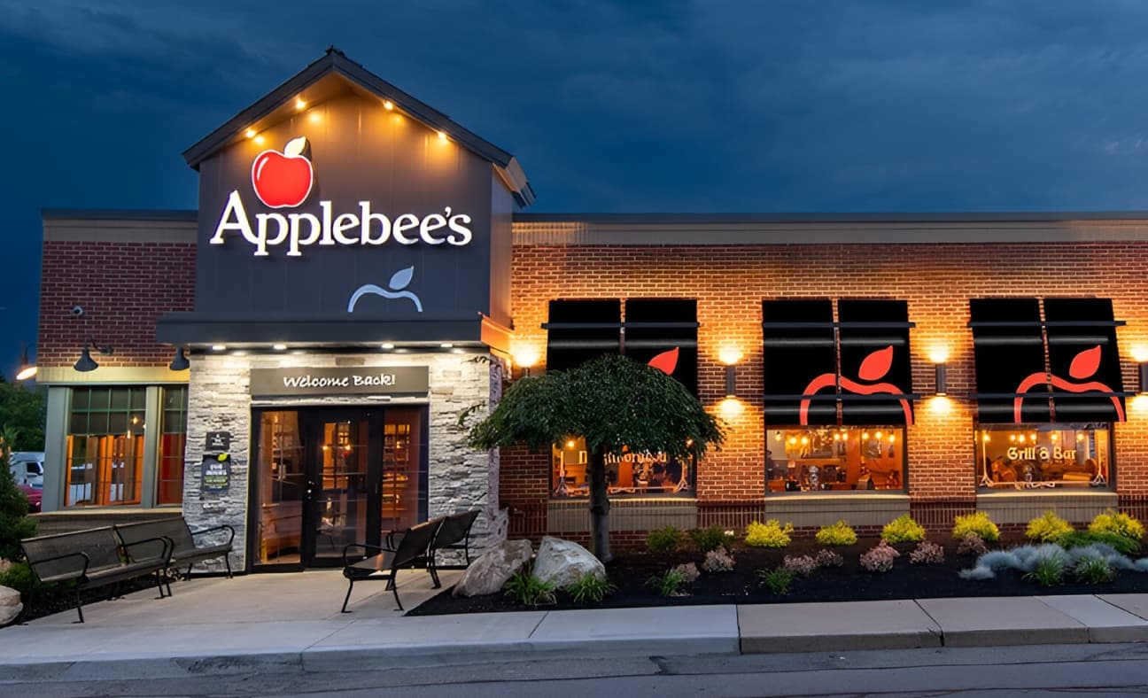 Exterior view of an Applebee's restaurant at dusk with illuminated Applebee's signage and lighting.