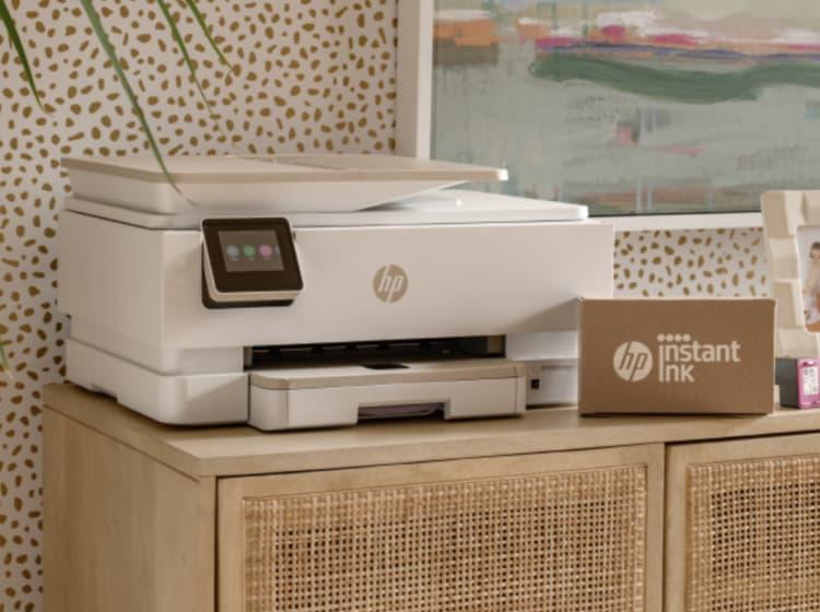 A white HP printer is on a wooden cabinet beside a cardboard box labeled "HP Instant Ink app" and ink cartridges, reflecting the tools of a successful company case study by ArcTouch.