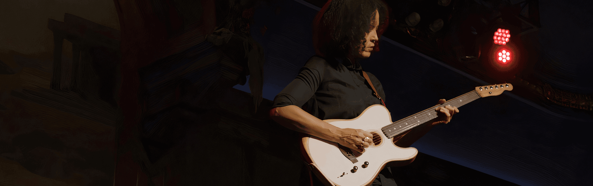 A person is playing a Fender guitar on stage under red lighting.