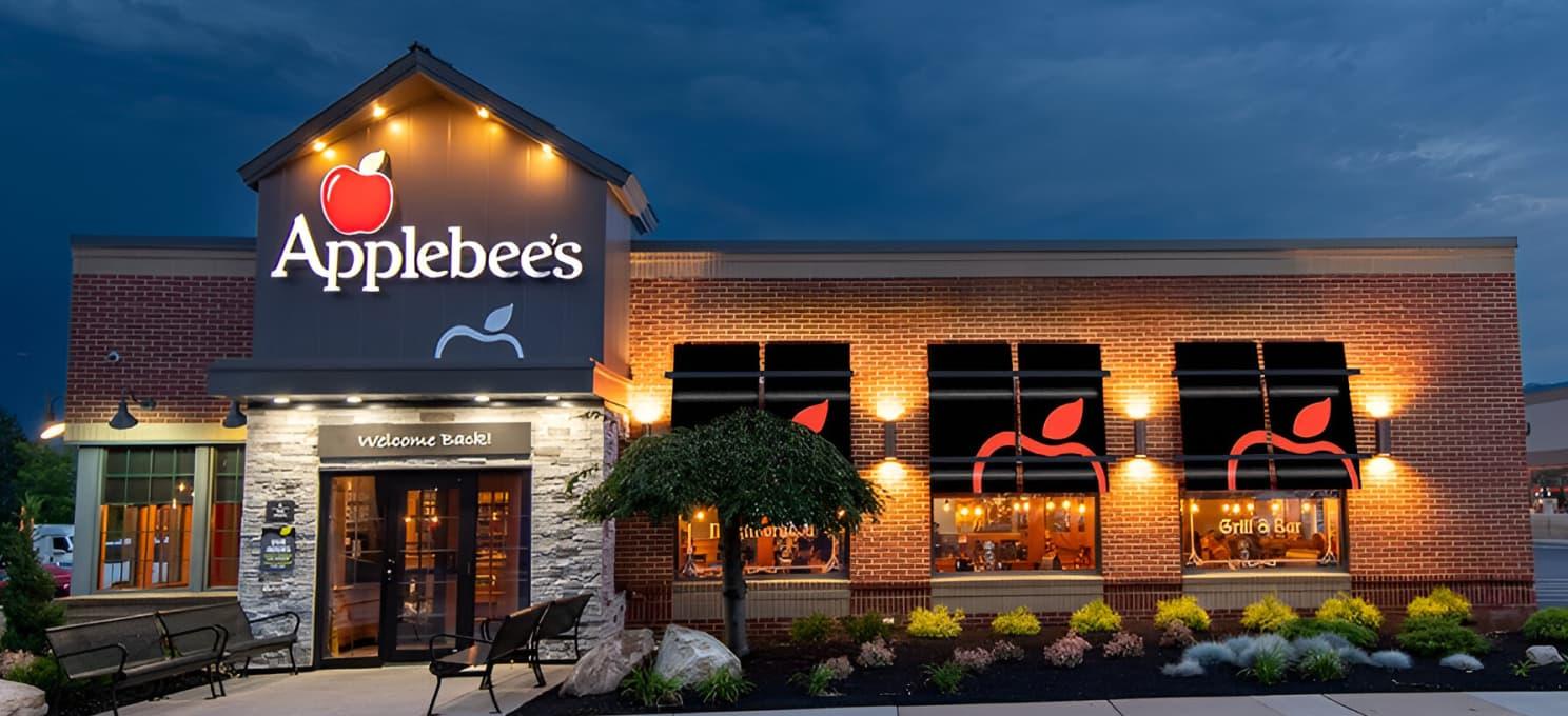 Exterior view of an Applebee's restaurant at dusk with illuminated Applebee's signage and lighting.