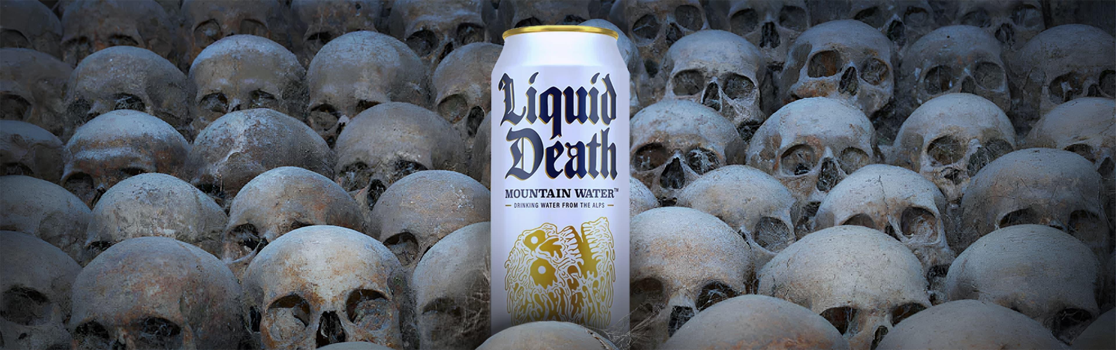 A can of Liquid Death is placed among an array of human skulls.