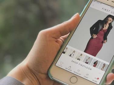 Person holding a smartphone displaying the GUESS jeans app with a woman modeling a red dress and black jacket on the screen, showcasing a perfect case study of modern mobile shopping experiences.