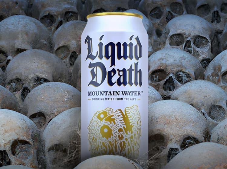 A can of Liquid Death is placed among an array of human skulls.