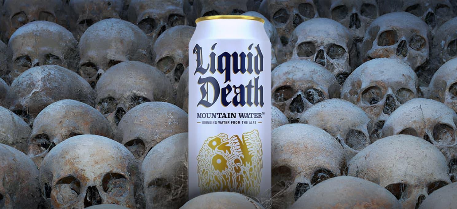 A can of Liquid Death is placed among an array of human skulls.