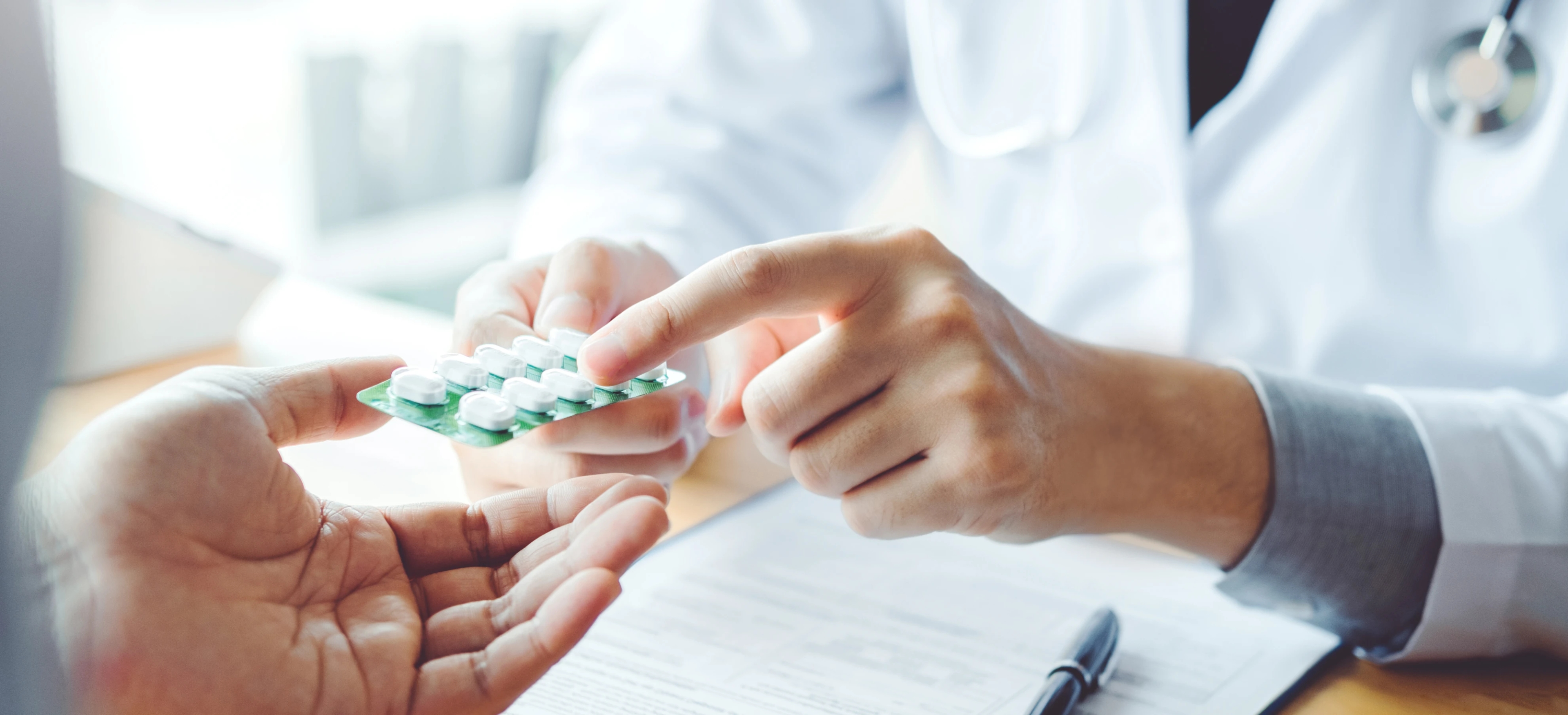 Close-up view of a doctor handing a blister pack of pills to a patient