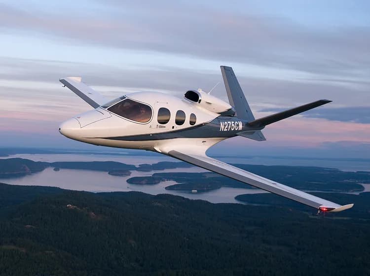 A Cirrus Vision Jet flying over a scenic landscape.