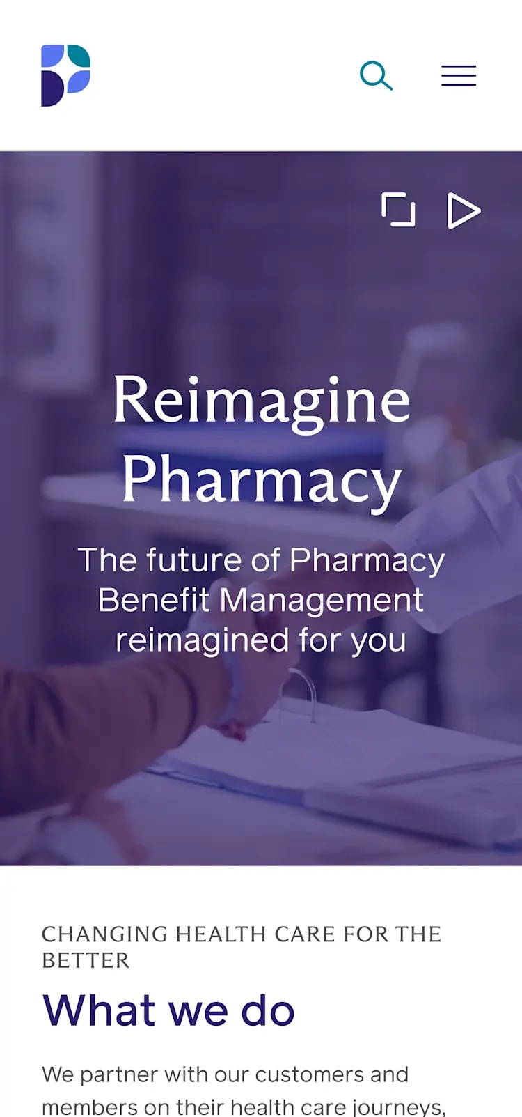 Screenshot of the Prime Therapeutics website in mobile view.  
The top section displays Prime's logo, a search magnifying glass icon, and a horizontal menu bar.
Below the header, a prominent banner displays the text "Reimagine Pharmacy" in a large, bold font. 
Smaller text underneath explains "The future of Pharmacy Benefit Management reimagined for you."
A blurred background image, in a muted purplish-blue tone, is visible, featuring two hands shaking hands.
Further down, "CHANGING HEALTH CARE FOR THE BETTER" is displayed in a smaller font. 
The heading "What we do" is present in a larger font, indicating a section about the company's services.