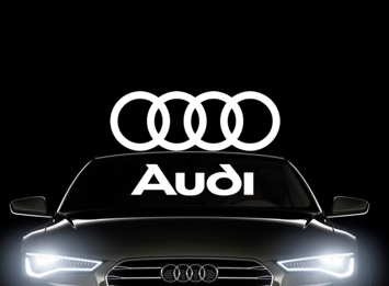 White Audi logo in front of A6 with headlights on